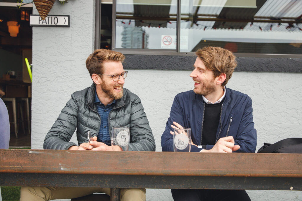 Two friends laughing at a high-top table.